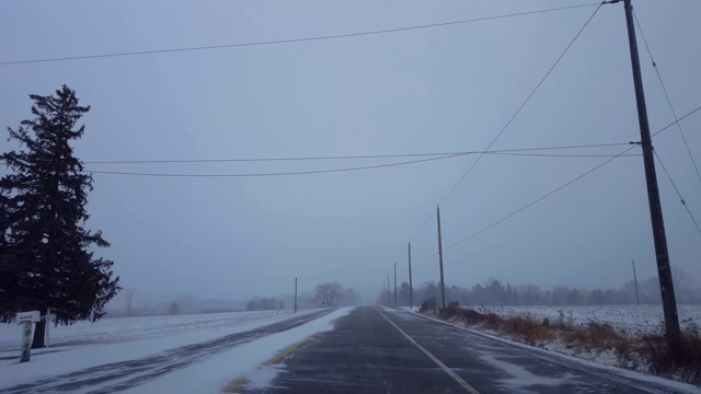 在乡村公路上行驶着冬日暴风雪。司机观点:下雪了，乡下路上下雪了。视频素材