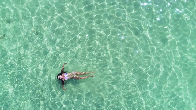 在蓬塔卡纳，多米尼加共和国，美丽的女人在透明的绿松石加勒比海游泳鸟瞰图。夏天的海景与少女，美丽的海浪，蔚蓝的水在阳光灿烂的日子。视频素材