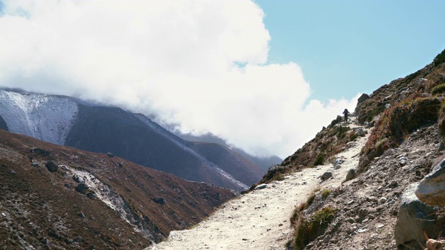 一名徒步旅行者在登博切附近的珠峰大本营徒步路线上，沿着伊姆贾霍拉山谷的小路行走的4K视频。背包客背着背包，用拐杖。视频素材