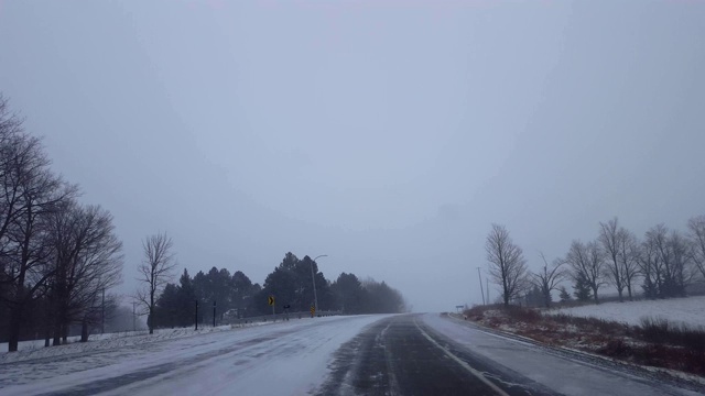 *明亮版本*驾驶上坡在道路弯曲在冬季暴风雪在白天。司机的观点，下雪的暴风雪下雪的农村道路。视频素材