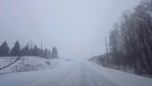 *明亮版本*驾驶白雪皑皑的天气在危险的道路条件在冬天。司机观点POV暴风雪暴风雪白色在远处。视频素材