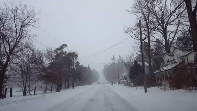 *明亮版本*驱动冬季暴风雪在住宅郊区在白天。郊区公路上下着大雪。视频素材