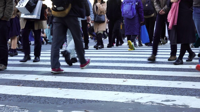 4K低角度视角的城市景观，拥挤的人群，男女游客步行穿过涩谷街，在日本东京涩谷的道路上有红绿灯的人行横道视频素材