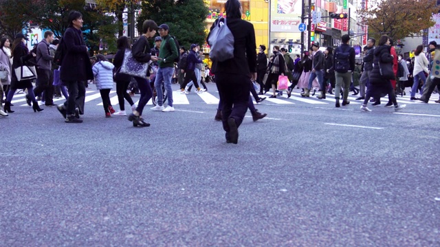 4K宽拍摄的城市景观，拥挤的商业人士，男人和女人与游客步行穿过涩谷街，在涩谷，东京市，道路上有交通灯和汽车的人行横道视频素材