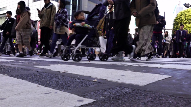 4K低角度视角的城市景观，拥挤的人群，男女游客步行穿过涩谷街，在日本东京涩谷的道路上有红绿灯的人行横道视频素材