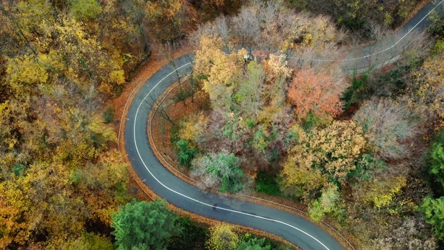 鸟瞰图的汽车通过弯曲的道路在森林。秋天高山峻岭。视频素材