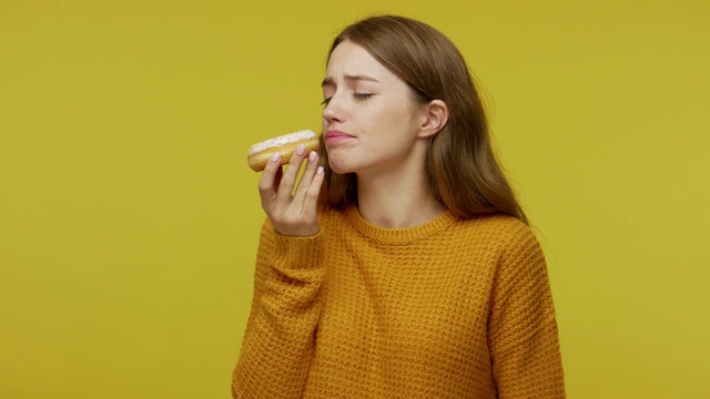 迷人积极的女孩望着美味的甜甜圈，欲求诱惑吃甜甜甜圈视频素材