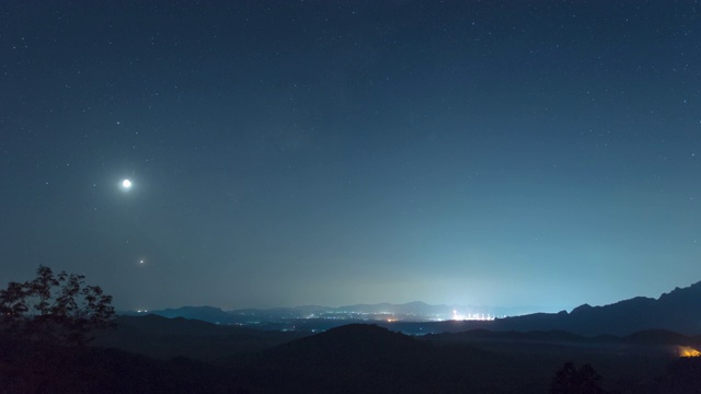 延时4k视频。泰国南邦梅莫，在迷雾笼罩的夜空中，长时间曝光的山上，星星排列(土星、月亮、金星、木星)的现象。视频素材