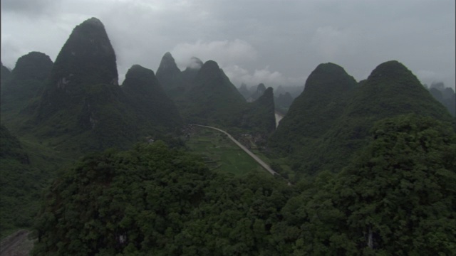 在一个阴天，一条河流蜿蜒穿过中国南方森林茂密的山脉。视频素材