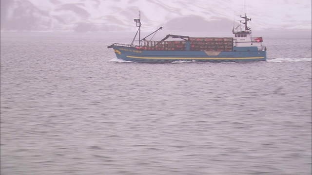 一只捕蟹船驶过荒野地区的海岸悬崖。视频素材