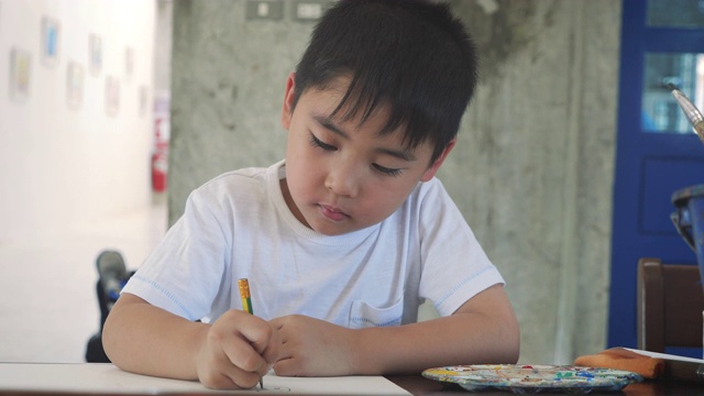 亚洲小男孩在家或幼儿园用铅笔在纸上画画，回到学校和教育理念视频素材