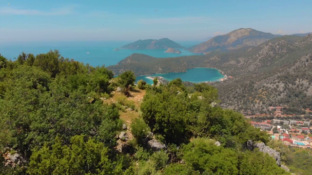 鸟瞰图的夏季城市附近的山和海水。飞山之上视频下载