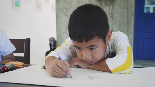 亚洲小男孩在家或幼儿园用铅笔在纸上画画，回到学校和教育理念视频素材