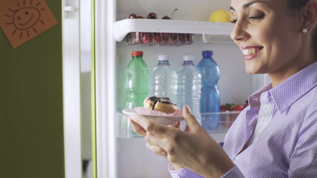 从冰箱里拿不健康食物的女人视频素材