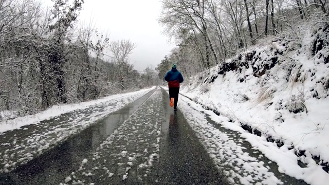 人在冬日森林里奔跑在覆盖着积雪的乡村小路上，动作缓慢视频素材