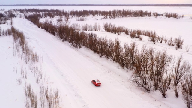 一辆汽车正行驶在冬日雪地上的乡间小路上。无人机鸟瞰图视频素材