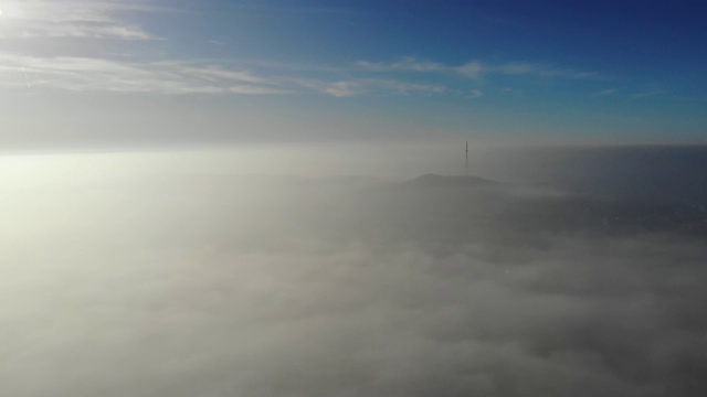 飞过云层。无人机凌晨拍摄的视频。烟雾高于城市。看城市电视塔。实时录像。4 k视频素材