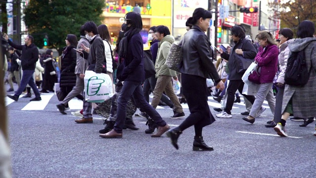 慢镜头城市景观和城市生活的亚洲拥挤的行人，男人和女人与游客步行穿过涩谷十字路口的红绿灯人行横道，东京市，日本视频素材