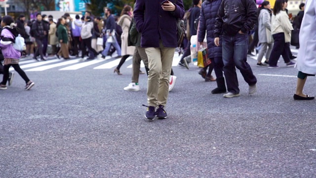 慢镜头城市景观和城市生活的亚洲拥挤的行人，男人和女人与游客步行穿过涩谷十字路口的红绿灯人行横道，东京市，日本视频素材