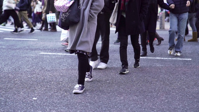 慢镜头城市景观和城市生活的亚洲拥挤的行人，男人和女人与游客步行穿过涩谷十字路口的红绿灯人行横道，东京市，日本视频素材