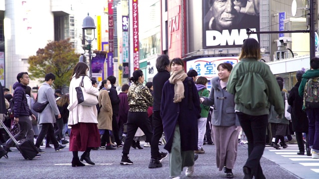 慢镜头城市景观和城市生活的亚洲拥挤的行人，男人和女人与游客步行穿过涩谷十字路口的红绿灯人行横道，东京市，日本视频素材