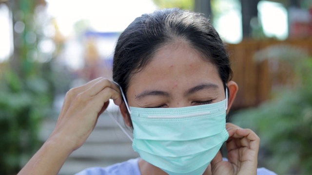 慢动作年轻的亚洲女性咳嗽并戴上防护口罩，以防止细菌和空气污染，保健理念视频素材