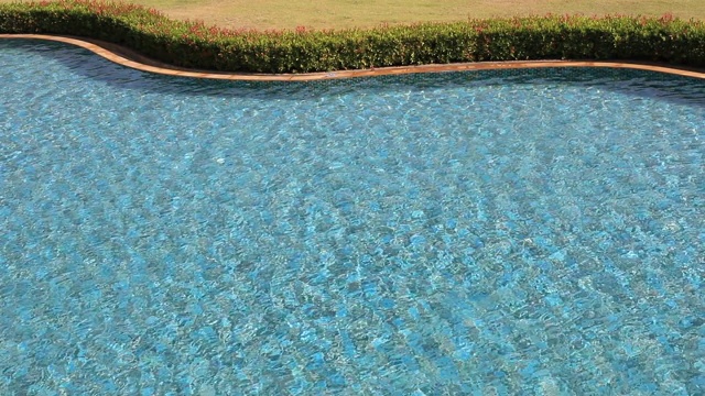 度假酒店的游泳池，以蓝色的海浪为背景，荡漾、流动。夏季背景概念。俯视图与慢动作。视频素材