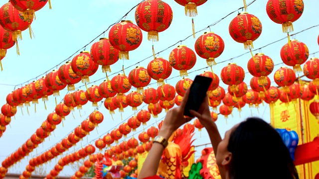 女人拍照的许多中国灯笼在神社。彩灯上的祝福文字寓意拥有财富和幸福视频素材