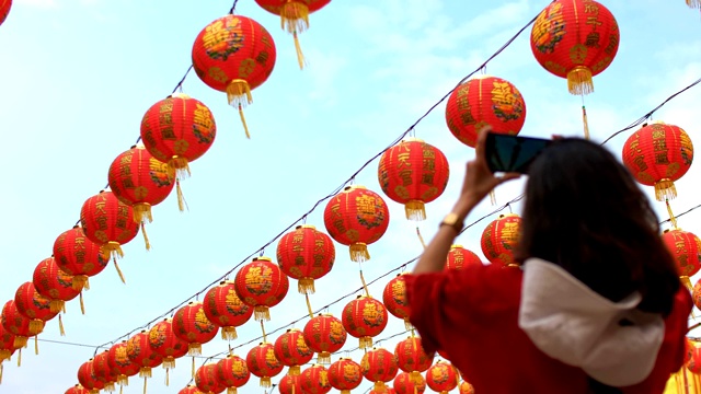 女人拍照的许多中国灯笼在神社。彩灯上的祝福文字寓意拥有财富和幸福视频素材