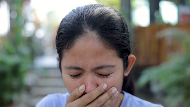 慢动作年轻的亚洲女性咳嗽并戴上防护口罩，以防止细菌和空气污染，保健理念视频素材