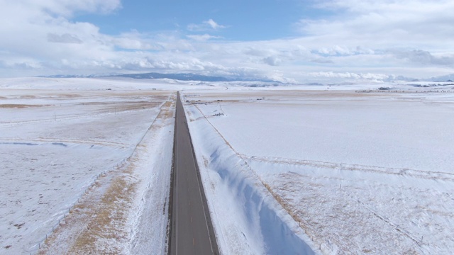 天线:在蒙大拿州的空旷的柏油公路上飞过白雪皑皑的平原视频素材