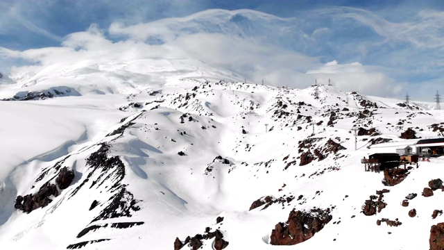 鸟瞰图站滑雪缆车与小屋高在高加索山脉在度假胜地厄尔布鲁斯在冬季。车站及索道概况视频素材