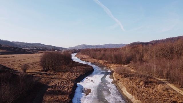 无人机拍摄的是深秋的森林和乡村冰冷的河流。深秋的森林山丘。鸟瞰图森林。视频下载