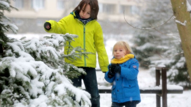 可爱的蹒跚学步的男孩，在操场上玩雪视频素材