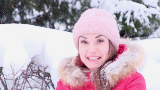 在一个阳光明媚的冬日，穿着红色夹克的年轻女子在空中抛雪视频素材