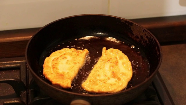 面饼是在平底锅里热油里煎的。一个人翻饼。视频素材