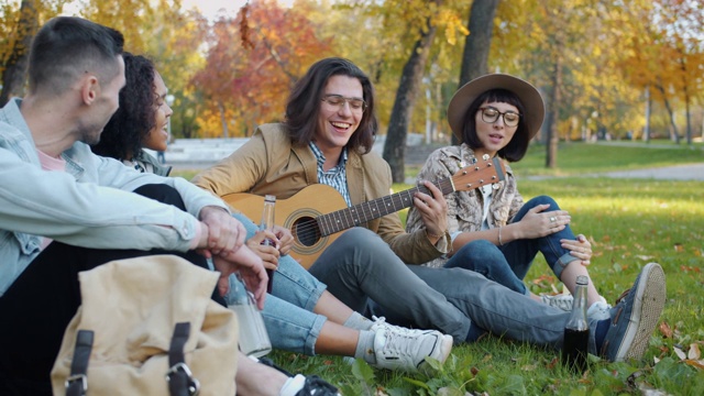 慢镜头，欢快的男孩和女孩在公园里玩吉他唱歌视频素材