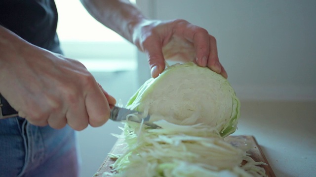 慢镜头男子用切菜刀切卷心菜准备做素食沙拉视频素材