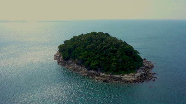 飞向热带岛屿，石质海岸和绿色的森林顶部，棕榈树冠在浓密的杂草丛生的灌木丛中。泰国普吉岛附近的自然风光。Ko聚氨酯视频素材