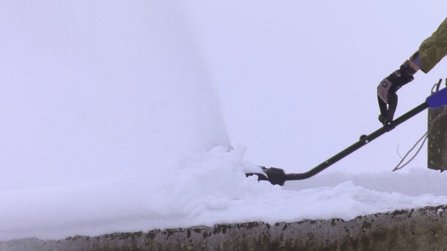 用扫雪机从屋顶上除雪。一个工人用吹雪机除雪。视频素材