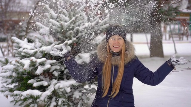 一个年轻的女人在公园里向空中抛雪。Slowmotion拍摄视频素材