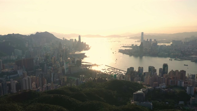 鸟瞰图香港城市天际线日出和太阳耀斑4K股票视频。飞越自然，从山上飞到城市。视频素材