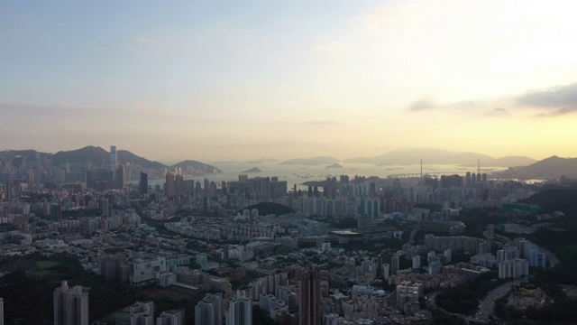 无人机从山头飞向香港市区的鸟瞰图，以全景城市天际线为背景的4K早间股票视频。视频素材