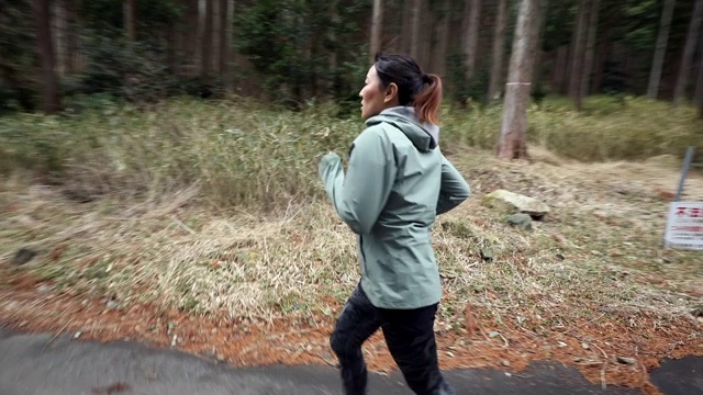 一个女人在山林路上慢跑视频素材