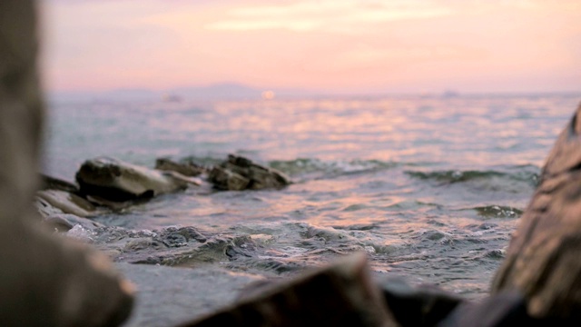 特写慢动作低角度小海浪翻滚在岩石海滩。海滨。傍晚的日落在卵石的海滩上视频素材