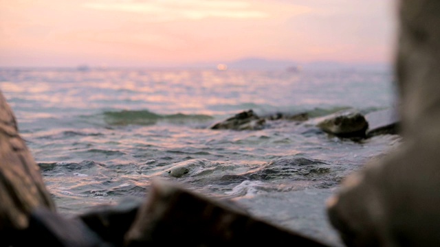 特写慢动作低角度小海浪翻滚在岩石海滩。海滨。傍晚的日落在卵石的海滩上视频素材