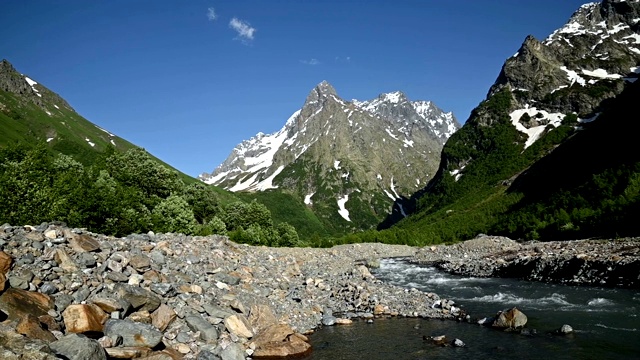 全景慢镜头岩石海岸的暴风雨的山区河流包围了林地和高岩石山脉的高加索。山景观背景视频素材