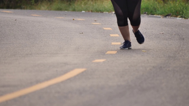 近距离女人的脚跑在道路上的公园。女性在晚上跑步。健康和健身。慢动作视频素材