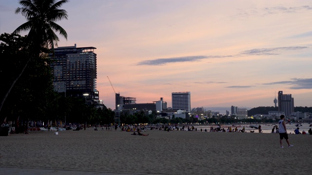 泰国芭堤雅海滩上的4K日落。在初夏的傍晚，游客和家人一起享受海滩和大海。视频素材