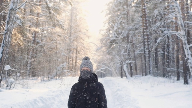 肖像少年在冬季编织帽子围巾在冬季雪林。视频素材